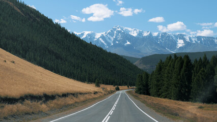 Road trip on summer vacation. Driving on empty asphalt road dangerous mountain pass. View snow...