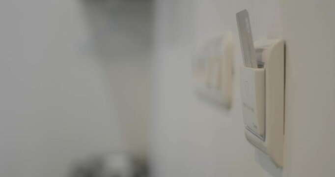close up of a man's hand inserting the room key in the card holder to switch on the electricity to his hotel room.
