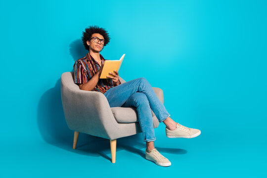 Full body portrait of nice young man sit chair hold book look empty space wear shirt isolated on turquoise color background