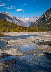 Shallow river flowing from glacier mountains in autumn