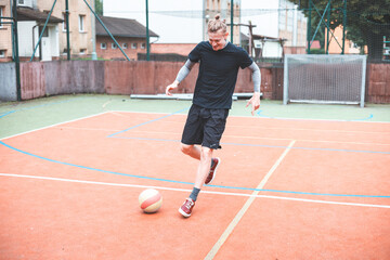 Young man focuses on controlling a football on an outdoor court. He carefully juggles the ball with precision, surrounded by an urban backdrop of buildings and a goal, combining sports and skill