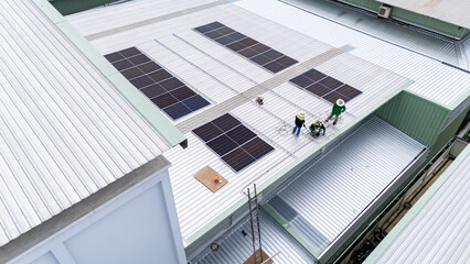 Builder mounting photovoltaic solar modules on roof of house. Back view of man engineer in helmet installing solar panel system outdoors. Concept of alternative and renewable energy.