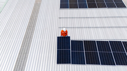 Builder mounting photovoltaic solar modules on roof of house. Back view of man engineer in helmet installing solar panel system outdoors. Concept of alternative and renewable energy.