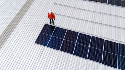 Builder mounting photovoltaic solar modules on roof of house. Back view of man engineer in helmet installing solar panel system outdoors. Concept of alternative and renewable energy.