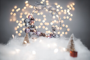 Christmas deoration concept on holidays with a silver derr, white fake snow for a festive december. In the background are bokeh balls made of lights