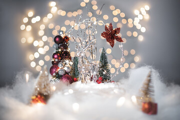 Christmas deoration concept on holidays with a glass derr, white fake snow for a festive december. In the background are bokeh balls made of lights