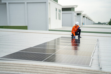 Builder mounting photovoltaic solar modules on roof of house. Back view of man engineer in helmet installing solar panel system outdoors. Concept of alternative and renewable energy.