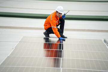 Builder mounting photovoltaic solar modules on roof of house. Back view of man engineer in helmet installing solar panel system outdoors. Concept of alternative and renewable energy.