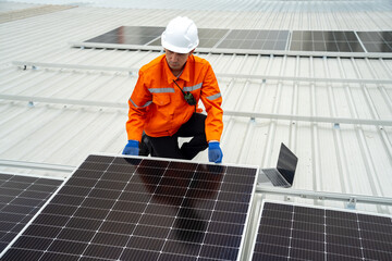 Builder mounting photovoltaic solar modules on roof of house. Back view of man engineer in helmet installing solar panel system outdoors. Concept of alternative and renewable energy.