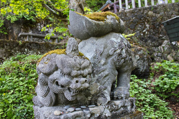 Moss-covered stone Komainu guardian lion-dog statue at Japanese shrine