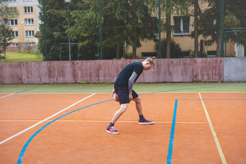 Basketball player controls and dribble the ball during a casual game on an outdoor court, bending...