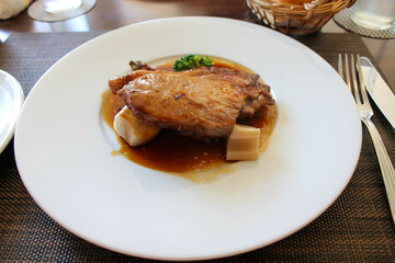 Roasted pork meat dish with brown sauce served on restaurant table