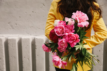 Woman in yellow jacket holding bouquet of peonies