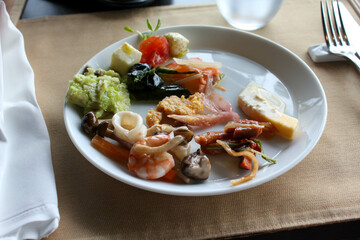 Appetizer plate with shrimp salad and marinated vegetables at buffet