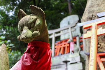 Stone fox statue with red bib at Fushimi Inari Shrine in Kyoto