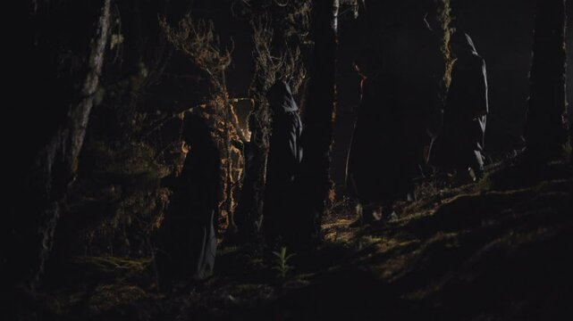 Dark monks walking down a mountain forest towards the village on a dark Halloween night