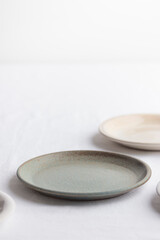 Empty rustic vintage plates dinnerware on a white tablecloth with copy space as a background for meal food dishes, food mock up