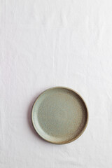 Empty rustic vintage green plate on a white tablecloth with copy space as a background for meal food dishes, food mock up