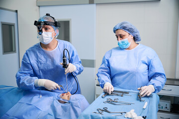 Surgeon with assistant working in sterile operating room using modern technologies