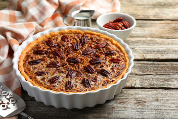 Delicious pecan pie in baking dish on wooden table, closeup