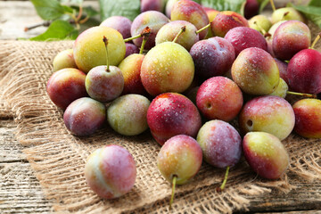 Pile of tasty ripe plums on wooden table, closeup