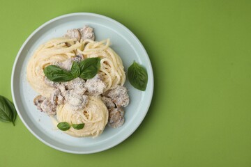 Delicious pasta with mushrooms and basil on light green background, top view. Space for text