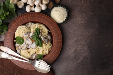 Delicious pasta with mushrooms and basil served on brown table, flat lay. Space for text
