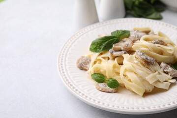 Delicious pasta with mushrooms and basil on light table, closeup. Space for text