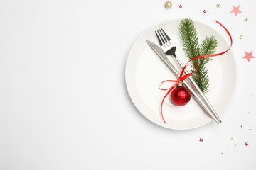 Christmas table setting with plate, cutlery and festive decor on white background, top view. Space...