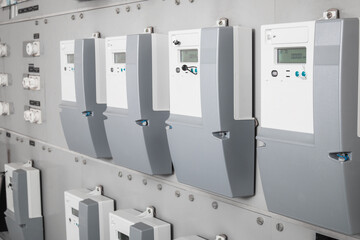 Many smart meters in electrical room of building with defocused ceramic fuses. Digital meter...