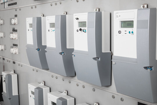 Many smart meters in electrical room of building with defocused ceramic fuses. Digital meter transmits energy consumption. Electric energy use is recorded and transmitted automatic. Selective focus.