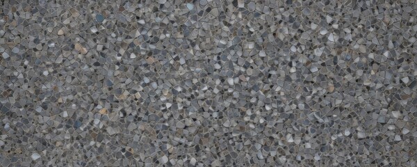 Fototapeta premium a close-up view textured surface composed of small, irregularly shaped stones or pebbles in various shades of gray, black, and white