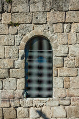 a section of an ancient stone wall with an arched iron grate window