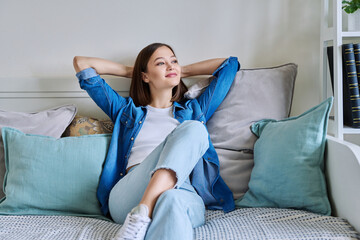 Relaxed young beautiful happy woman sitting on couch at home