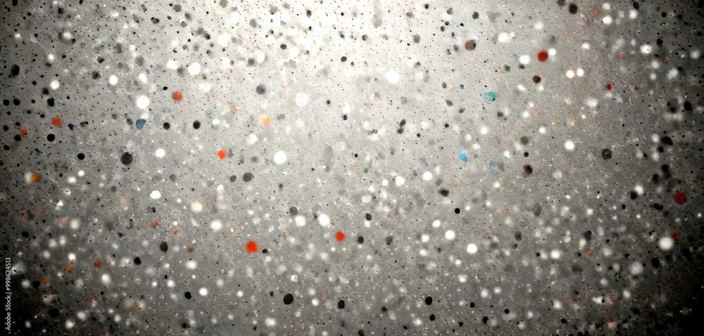 Poster a close-up view textured surface with a pattern of small, irregularly shaped dots in various shades of gray, black, and orange