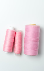 Pink thread spools on white background.