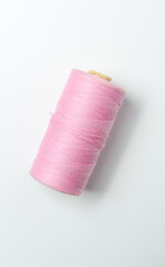 Pink thread spool on white background.