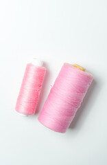 Pink thread spools on white background.