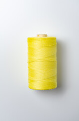 Yellow thread spool on white background.