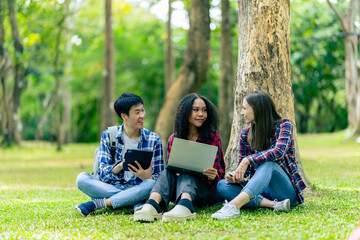 Group of Asian female college students talking and working together at university in a park discussing their studies together.