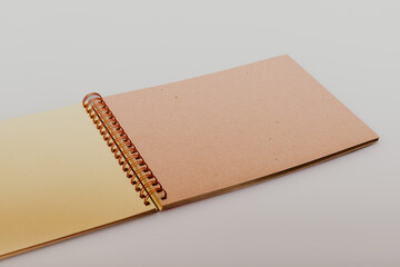 Beige and light yellow craft paper photo album with spiral binding on a white studio background. DIY scrapbooking, storing printed photos. Multiple angles of eco-friendly designed notebook.