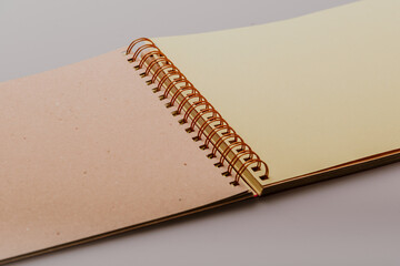 Beige and light yellow craft paper photo album with spiral binding on a white studio background....