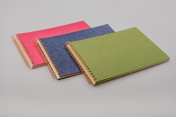 Stack of three colourful craft paper spiral binding photo albums in blue, green, and magenta. Ideal for DIY scrapbooking, memory keeping, and creative photo displays in vibrant styles.