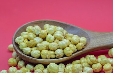 Roasted Bengal Gram or Garbanzo Bean in a Wooden Spoon Isolated on Red Background with Copy Space, Also Known as Chickpea or Egyptian Pea