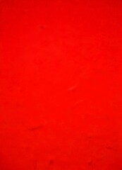 Fototapeta premium a close-up view red surface with a slight texture, resembling a fabric or a canvas The color is vibrant and the background is blurred, drawing attention to the red surface