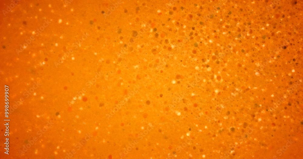 Poster a close-up view textured orange surface with numerous small white dots scattered across it, creating a visually striking pattern