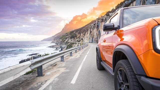 Coastal Road Trip Adventure. An orange SUV cruises along a scenic coastal highway at sunset, offering a sense of freedom and adventure.