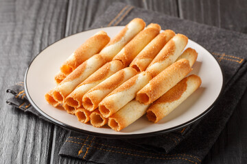 French sweet thin wafer tubes called Russian cigarettes close-up in a plate on the table. Horizontal