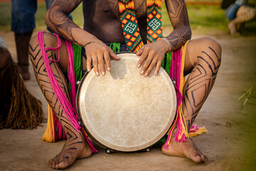 Sao Paulo, SP, Brazil - April 16 2023: Indigenous people with body paint and traditional accessories from the Huni Kuin culture playing djembê.