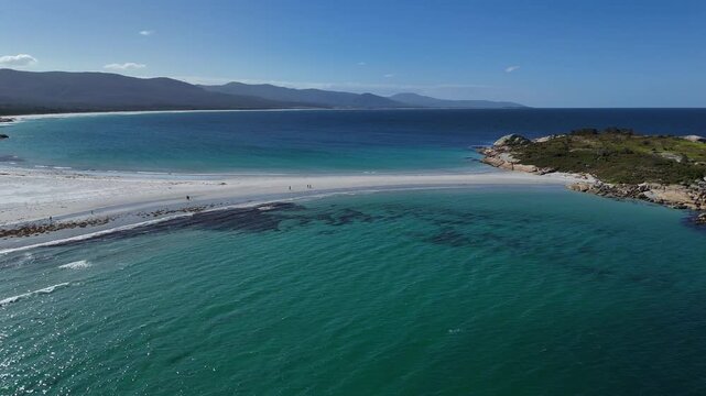 White sand beach with walking tourists at sandbar revealing Diamond Island, aerial dynamic